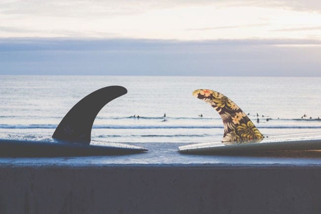 Visado de pareja fotografía de dos tablas de surf del revés y de fondo el mar y la puesta de Sol